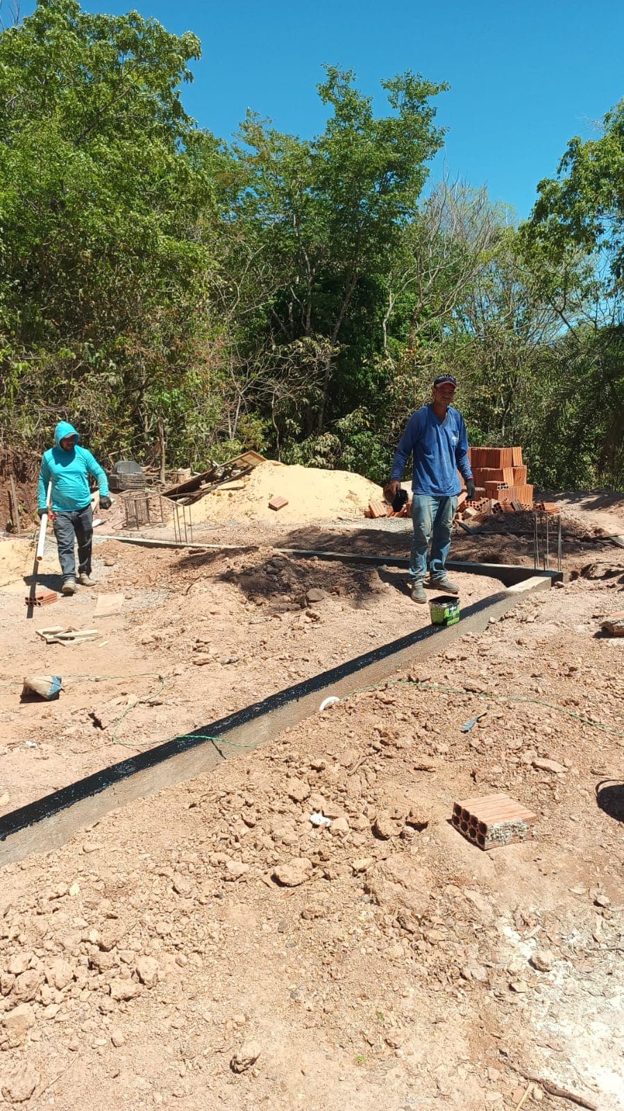 Trabalhadores junto à fundação e à base de concreto no início da reforma da sede.